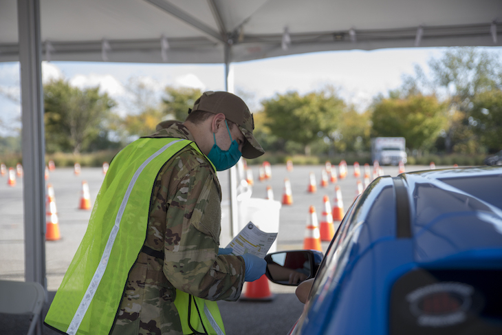 Member of the Delaware National Guard speaks with a member of the public during a drive-thru COVID-19 vaccine clinic.”